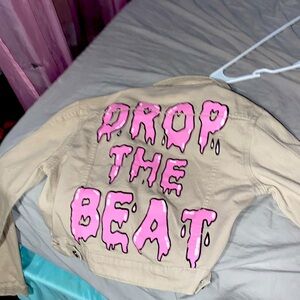 Beige jean jacket with pink wording never worn brought it too small. It’s an XS.